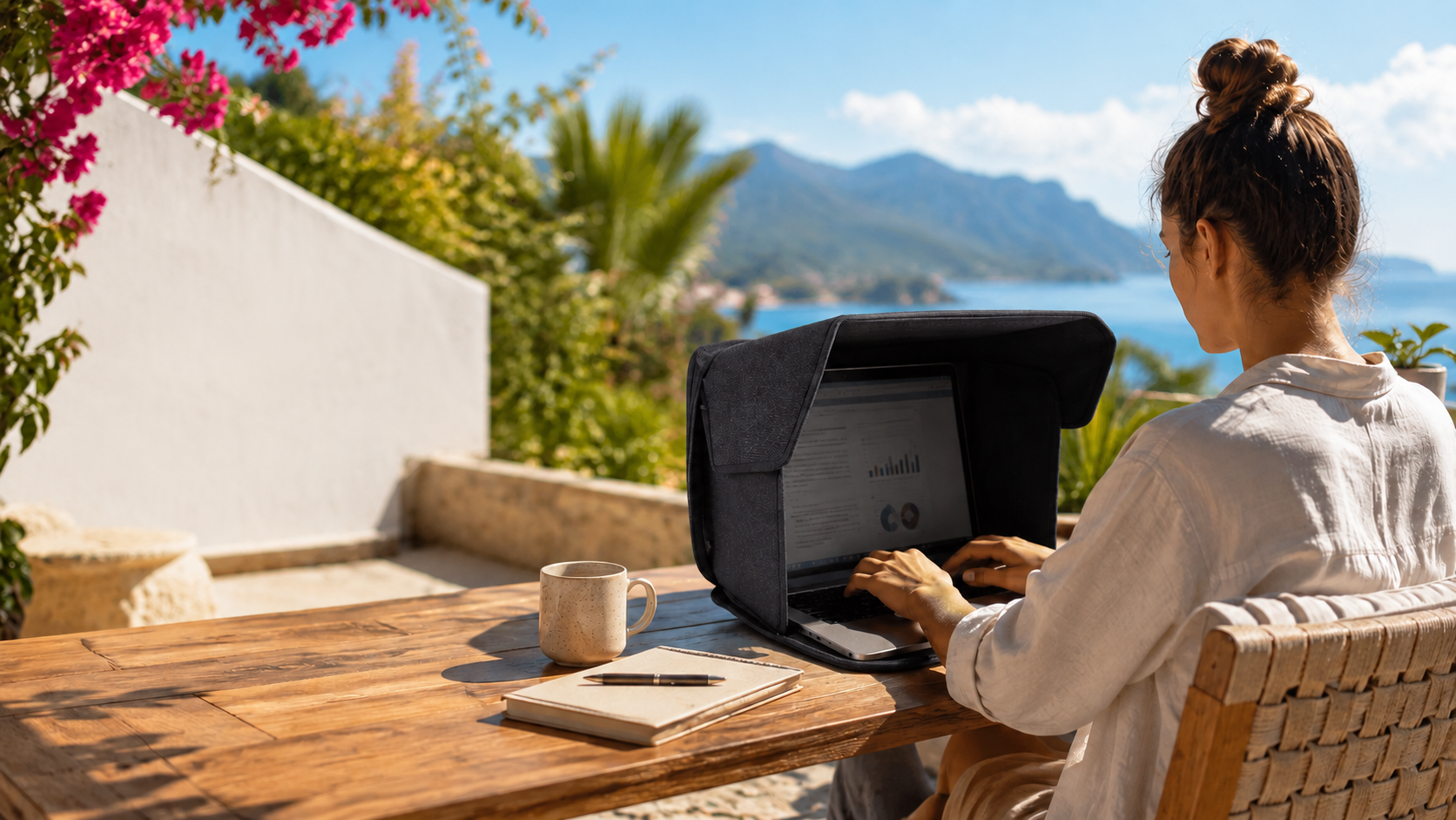Laptop mit Sonnenschutz beim mobilen Arbeiten auf einer sonnigen Terrasse